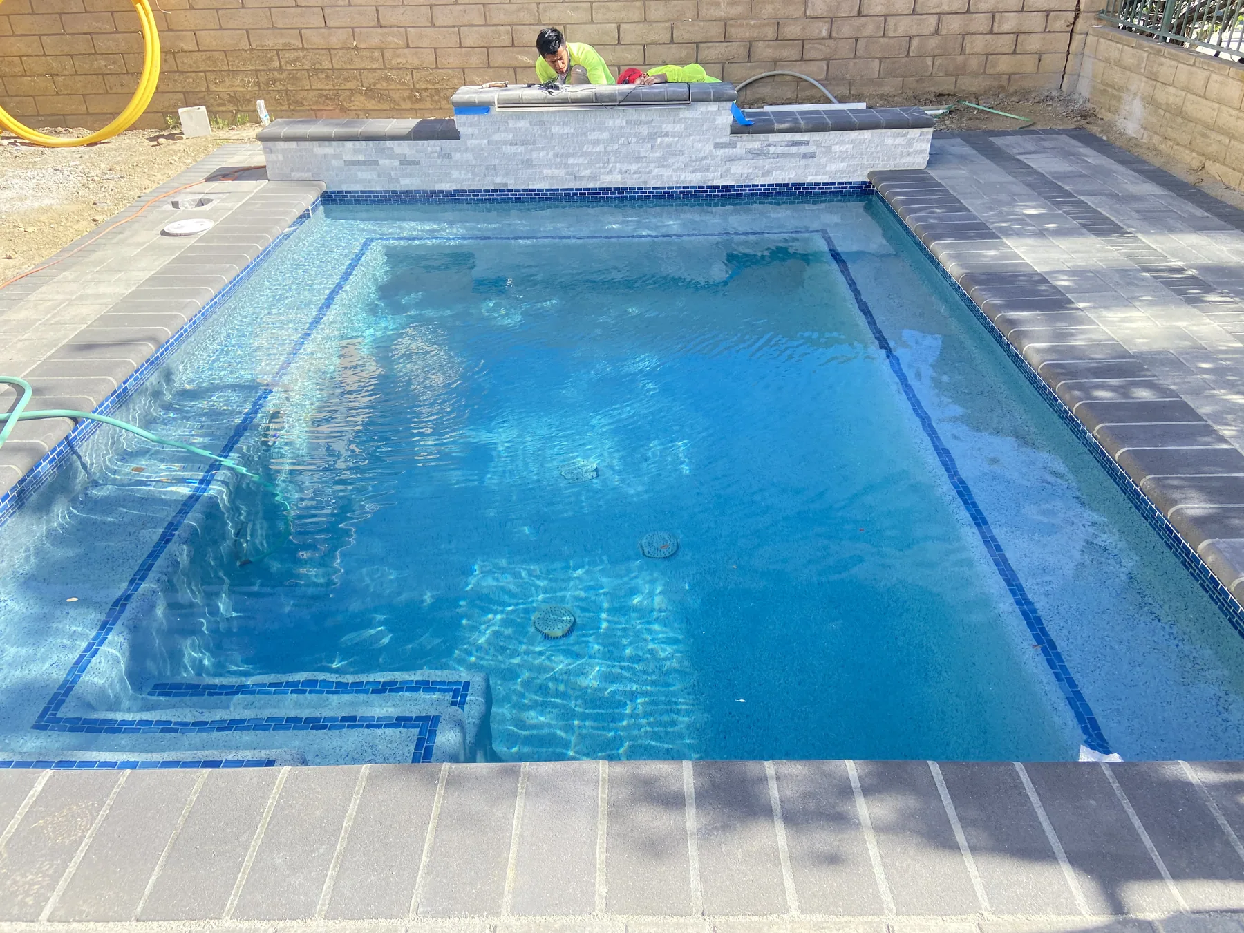 Finished pool with paver deck and raised wall