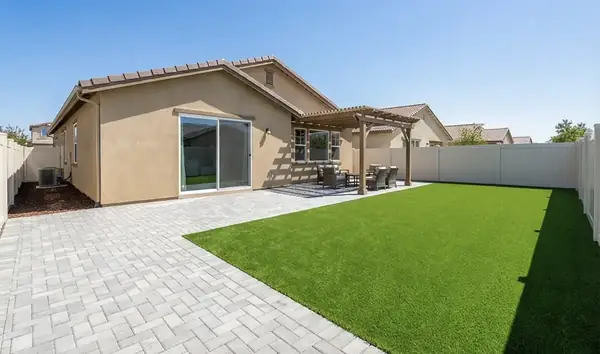 Backyard with turf, a paver patio and a pergola