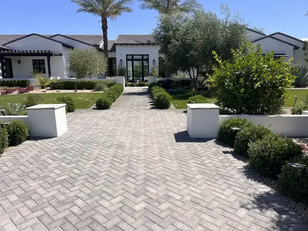 Wide paver driveway leading to a modern white house