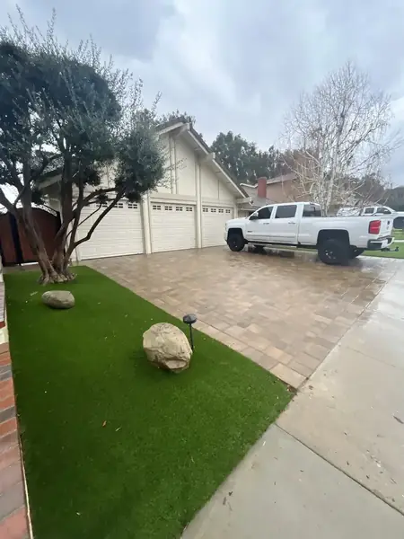 Front yard with turf lawn beside a paver driveway
