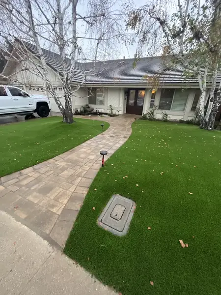 Curved paver walkway through a turf front lawn
