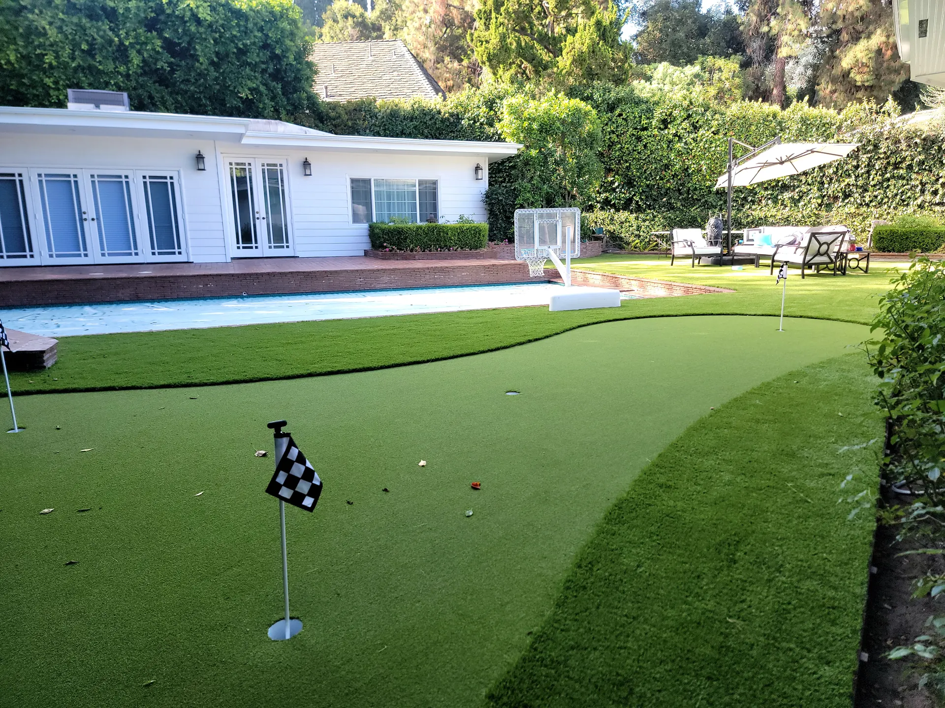 Backyard putting green next to a pool